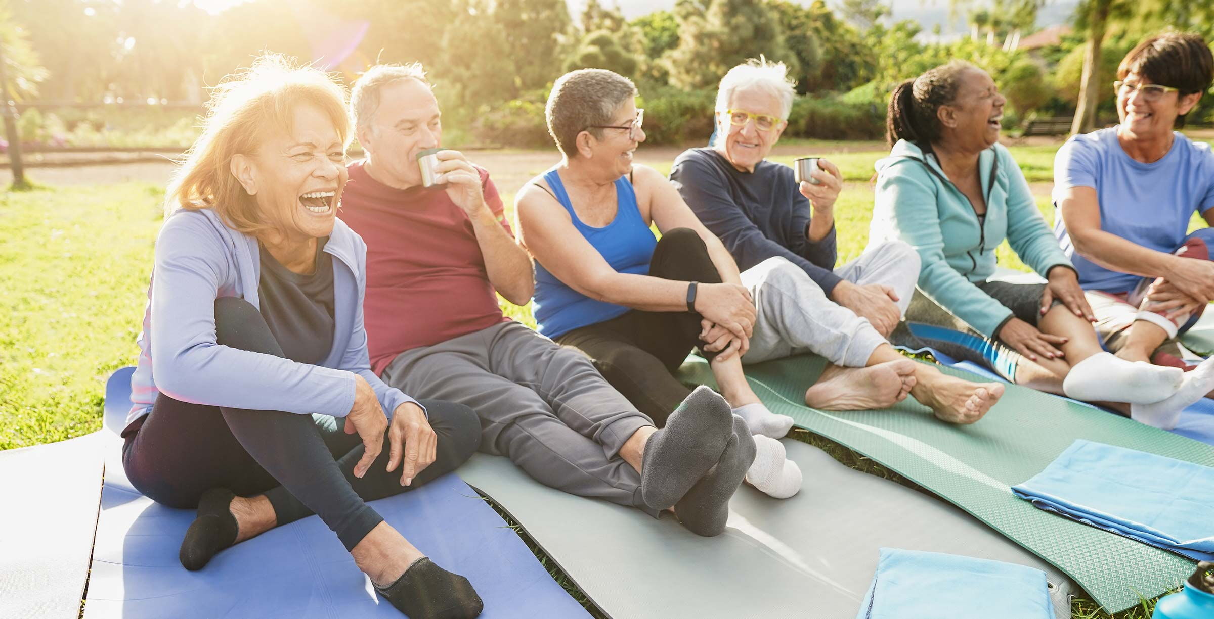 Senioren genießen Tee und lachen gemeinsam im Pflegenetzwerk auf einer Wiese in der Börde.