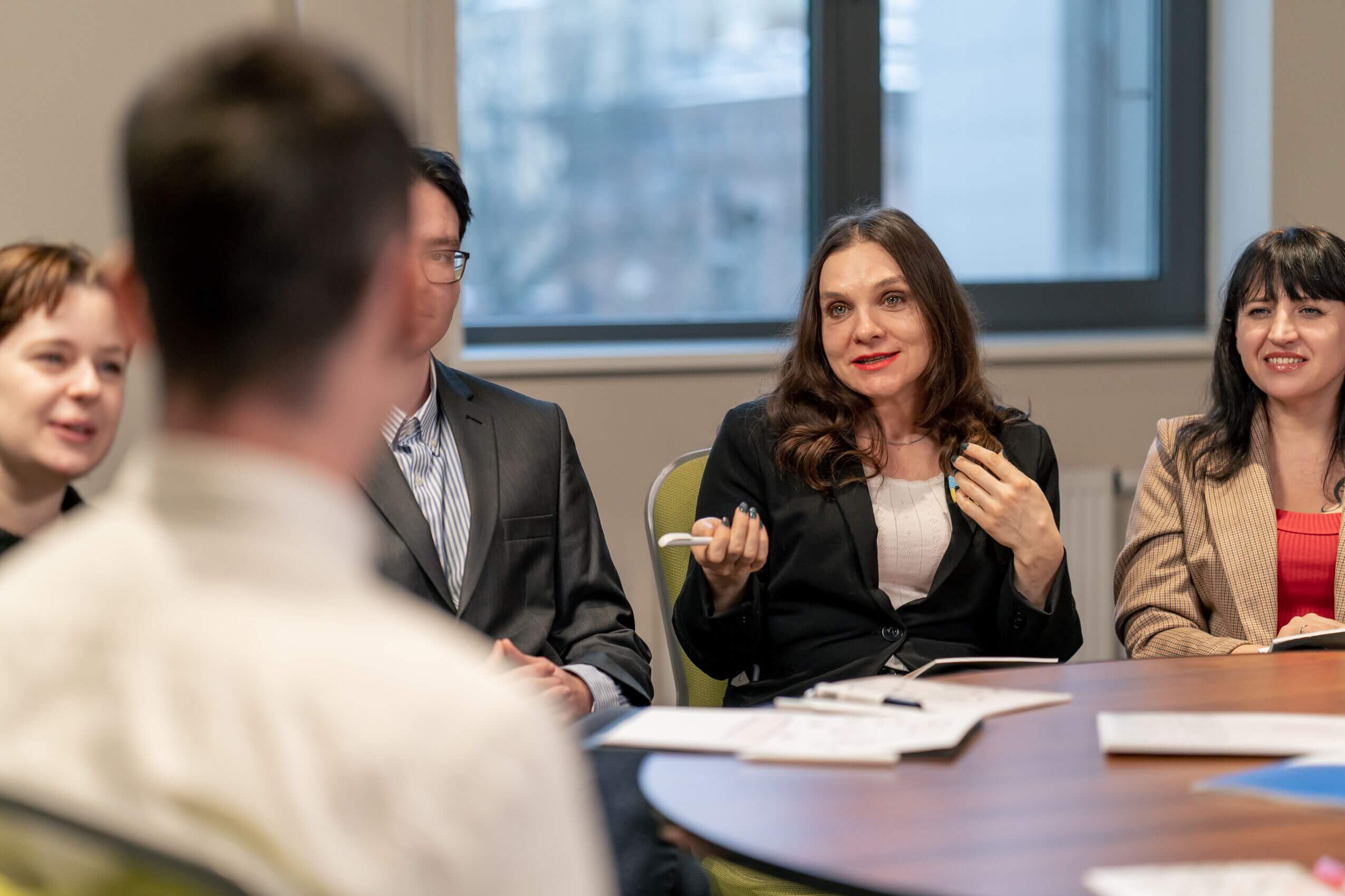 Partner diskutieren aktiv über Strategien im Pflegenetzwerk während eines Meetings am runden Tisch.